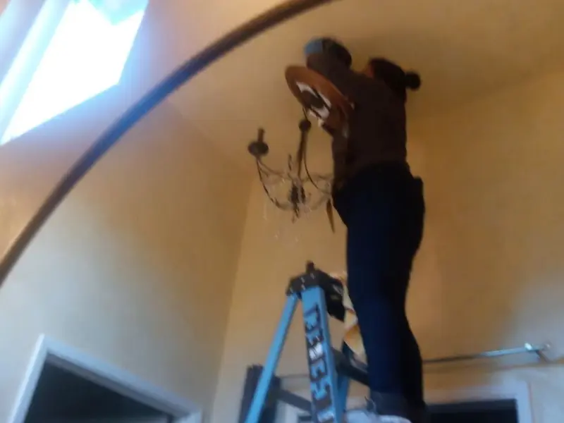 Electrician installing a chandelier in a Brutus residence